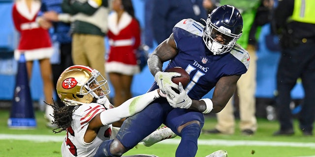 Tennessee Titans wide receiver A.J. Brown (11) catches a touchdown pass as he is defended by San Francisco 49ers cornerback Josh Norman, left, in the second half of an NFL football game Thursday, Dec. 23, 2021, in Nashville, Tenn.