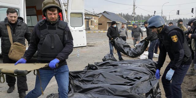 Volunteers and soldiers collect bodies of civilians killed by Russian forces at a destroyed bridge in Irpin, near Kyiv, Ukraine, Thursday, March 31, 2022. 