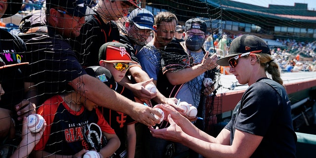 San Francisco Giants assistant coach Alyssa Nakken signs autographs for fans prior to a spring training baseball game against the Colorado Rockies Thursday, March 31, 2022, in Scottsdale, Ariz.