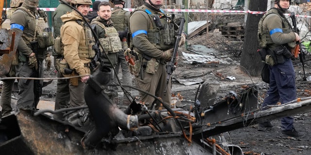 Ukrainian President Volodymyr Zelenskyy, center left, examines the site of a recent battle in Bucha, close to Kyiv, Ukraine, Monday, April 4, 2022.