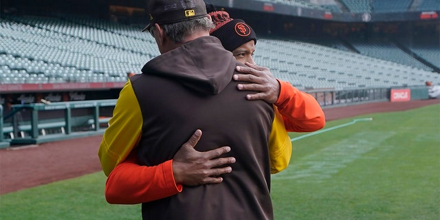 San Diego Padres third base coach Mike Shildt, back to camera, hugs San Francisco Giants first base coach Antoan Richardson after they spoke at a news conference before a game in San Francisco, Wednesday, April 13, 2022.