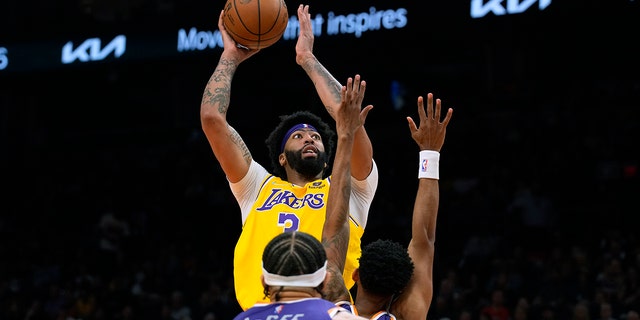 Los Angeles Lakers forward Anthony Davis shoots over Phoenix Suns center JaVale McGee and forward Mikal Bridges during the first half of an NBA basketball game Tuesday, April 5, 2022, in Phoenix.