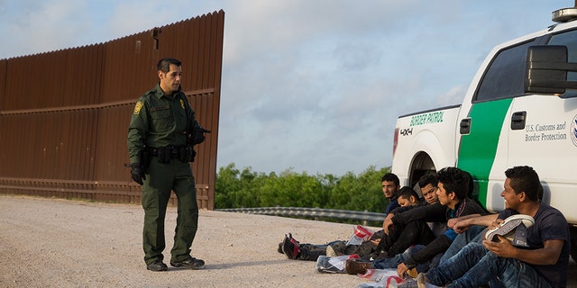 A Border Patrol agent apprehends illegal immigrants shortly after they crossed the border from Mexico into the United States on Monday, March 26, 2018 in the Rio Grande Valley Sector near McAllen, Texas.