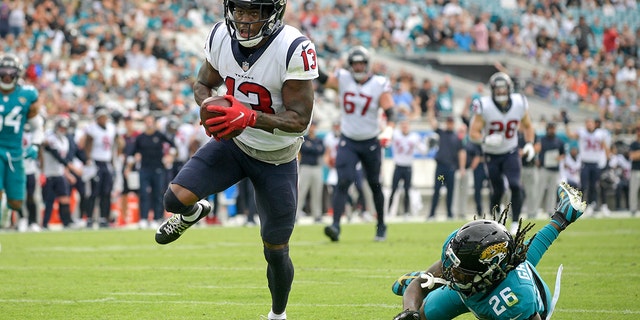 Houston Texans wide receiver Brandin Cooks (13) runs past Jacksonville Jaguars cornerback Shaquill Griffin (26) for a touchdown after a 22-yard reception during the first half of an NFL football game, Sunday, Dec. 19, 2021, in Jacksonville, Fla.