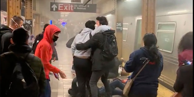 This photo provided by Will B Wylde, a person is aided outside a subway car in the Brooklyn borough of New York, Tuesday, April 12, 2022. A gunman filled a rush-hour subway train with smoke and shot multiple people Tuesday, leaving wounded commuters bleeding on a Brooklyn platform as others ran screaming, authorities said. Police were still searching for the suspect.