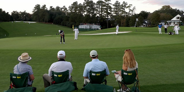 Patrons look on as Dustin Johnson putts on the 9th green during the Masters on Nov. 12, 2020, in Augusta, Georgia. 