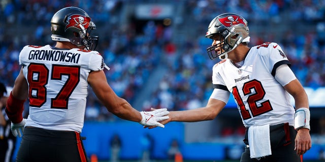 Tom Brady #12 and Rob Gronkowski #87 of the Tampa Bay Buccaneers react after a touchdown during the third quarter in the game against the Carolina Panthers at Bank of America Stadium on December 26, 2021 in Charlotte, North Carolina. 