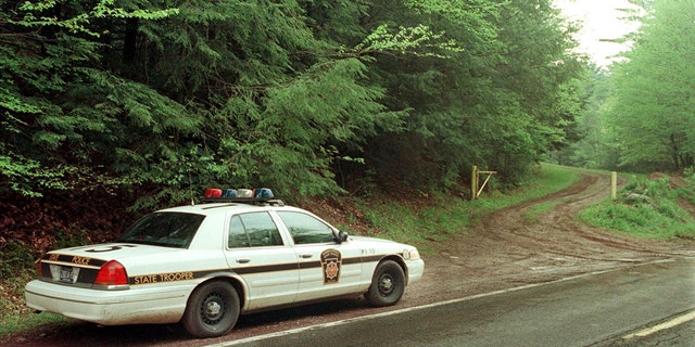 BEAR CREEK TOWNSHIP, UNITED STATES:  A Pennsylvania State Police Trooper guards the entrance to a service road leading to the area of the crash site of a twin engine aircraft that crashed 21 May, 2000.   AFP PHOTO/Tom MIHALEK (Photo credit should read TOM MIHALEK/AFP via Getty Images)