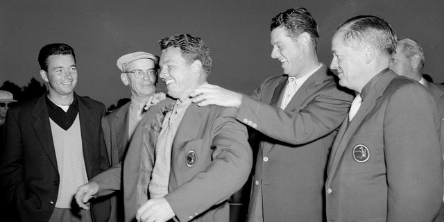 Ken Venturi, Clifford Roberts and Bobby Jones, far right, watch as Jack Burke, Jr. receives a Green Jacket from Cary Middlecoff during the 1956 Masters Tournament Presentation Ceremony at Augusta National Golf Club in April 1956 in Augusta, Georgia. 