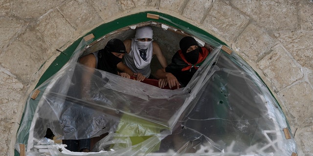 Masked Palestinians take position during clash with Israeli security forces at the Al Aqsa Mosque compound in Jerusalem's Old City Friday, April 15, 2022. 