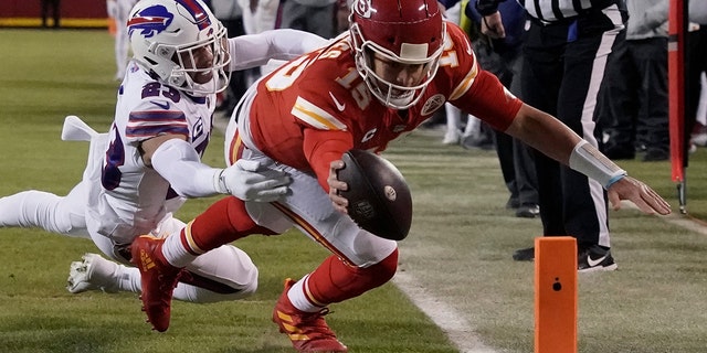 Kansas City Chiefs quarterback Patrick Mahomes (15) scores on an 8-yard touchdown run ahead of Buffalo Bills safety Micah Hyde (23) during the first half of an NFL divisional round playoff football game, Sunday, Jan. 23, 2022, in Kansas City, Mo.