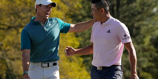 Rory McIlroy, of Northern Ireland, talks to Collin Morikawa after they both holed out from the bunker for a birdie during the final round at the Masters golf tournament on Sunday, April 10, 2022, in Augusta, Ga.