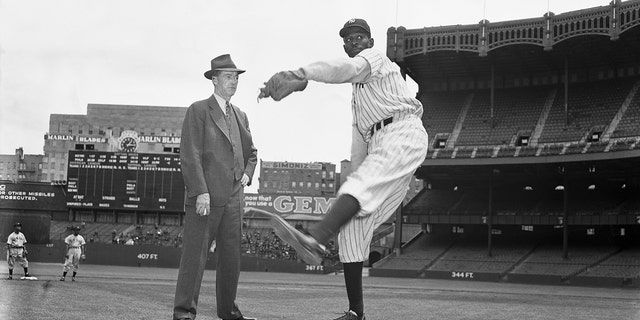 Baseball Hall of Famer Grover Cleveland Alexander stands on the pitcher's mound at Yankee Stadium and watches pitcher Satchel Paige at work. Paige was a member of the New York Black Yankees.