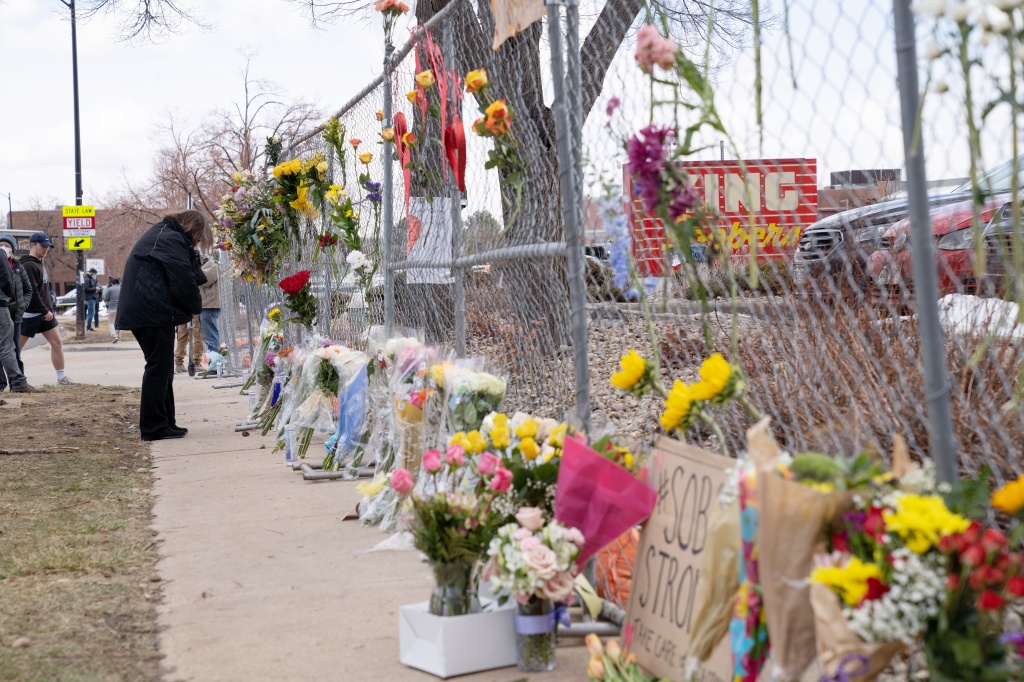 People lay flowers at a memorial near King Soopers supermarket where Ahmad Al Aliwi Alissa killed ten people including a police officer in Boulder, Colorado.