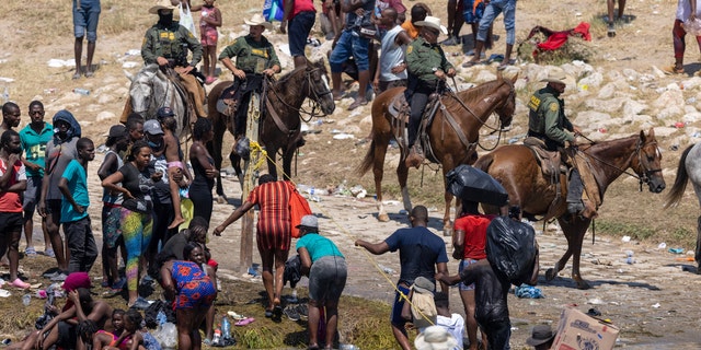 Mounted U.S. Border Patrol agents watch Haitian immigrants on the bank of the Rio Grande in Del Rio, Texas, Sept. 20, 2021 as seen from Ciudad Acuna, Mexico. 