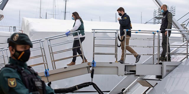 A U.S. federal agent and two Civil Guards board the yacht called Tango in Palma de Mallorca, Spain, Monday April 4, 2022. (AP Photo/Francisco Ubilla)