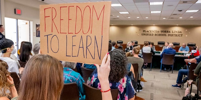 A student holds up a sign against banning CRT holds up a sign as members of the Placentia-Yorba Linda Unified School Board meet in Placentia on Wednesday, March 23, 2022.