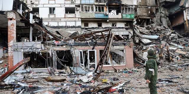 A serviceman stands at a building damaged during fighting in Mariupol, Ukraine, on April 13, 2022.