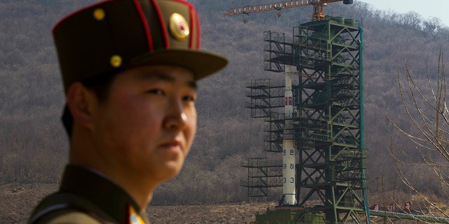 FILE - In this April 8, 2012, file photo, a soldier stands in front of the Unha-3 rocket at a launching site in Tongchang-ri, North Korea. (AP Photo/David Guttenfelder, File)