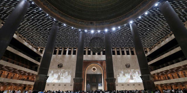 Indonesian Muslims pray spaced apart as they practice social distancing to curb the spread of the new coronavirus during an evening prayer called "tarawih" marking the first eve of the holy fasting month of Ramadan at Istiqlal Mosque in Jakarta, Indonesia, April 12, 2021. 