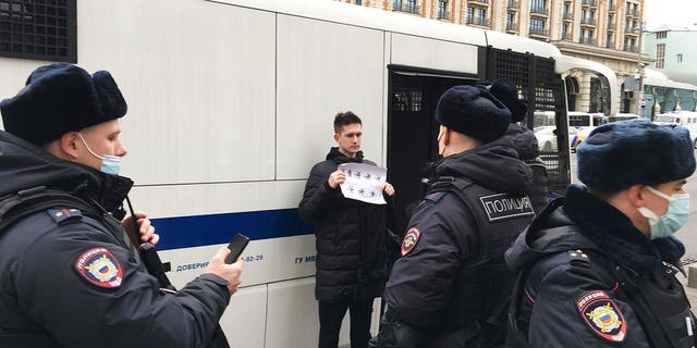 Dmitry Reznikov holds a piece of paper with eight asterisks that could have been interpreted as standing for "No to war" in Russian, stands next to a police van as he was detained in Moscow on March 13, 2022.