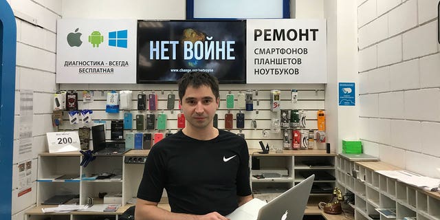 Marat Grachev, director of a shop that repairs Apple devices, poses with a sign in Russian that reads "No to war" in Moscow on March 16, 2022.