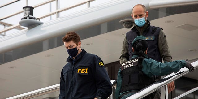 A U.S. federal agent walks past two Civil Guards on the yacht called Tango in Palma de Mallorca, Spain, Monday April 4, 2022.  (AP Photo/Francisco Ubilla)