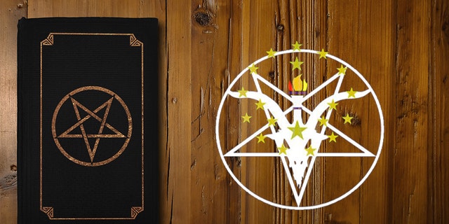 Close-up on a black book with an inverse pentagram on a brown wooden board.