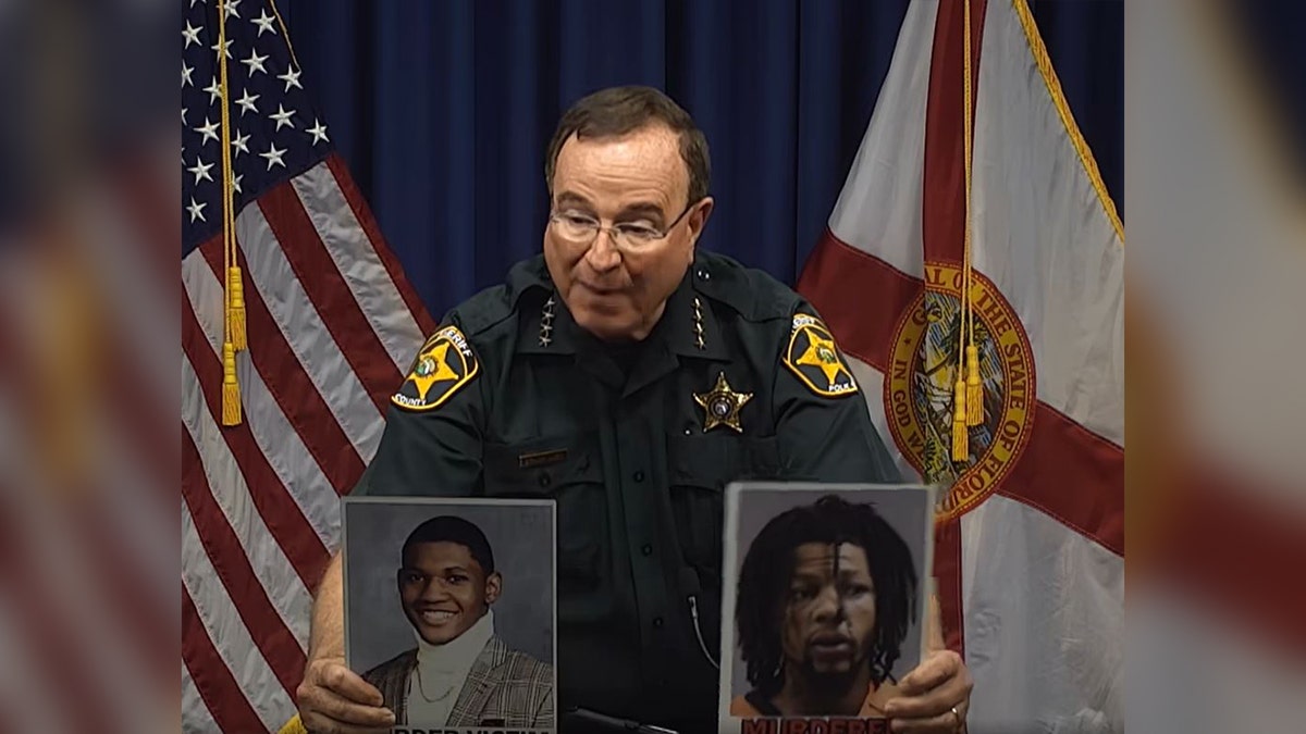 Sheriff Grady Judd holds up victim, suspect photos