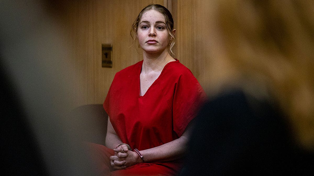 Woman in red prison garb with pink handcuffs