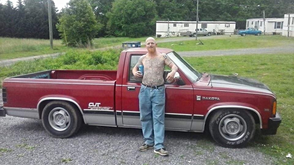 Don Steven McDougal poses shirtless next to a truck