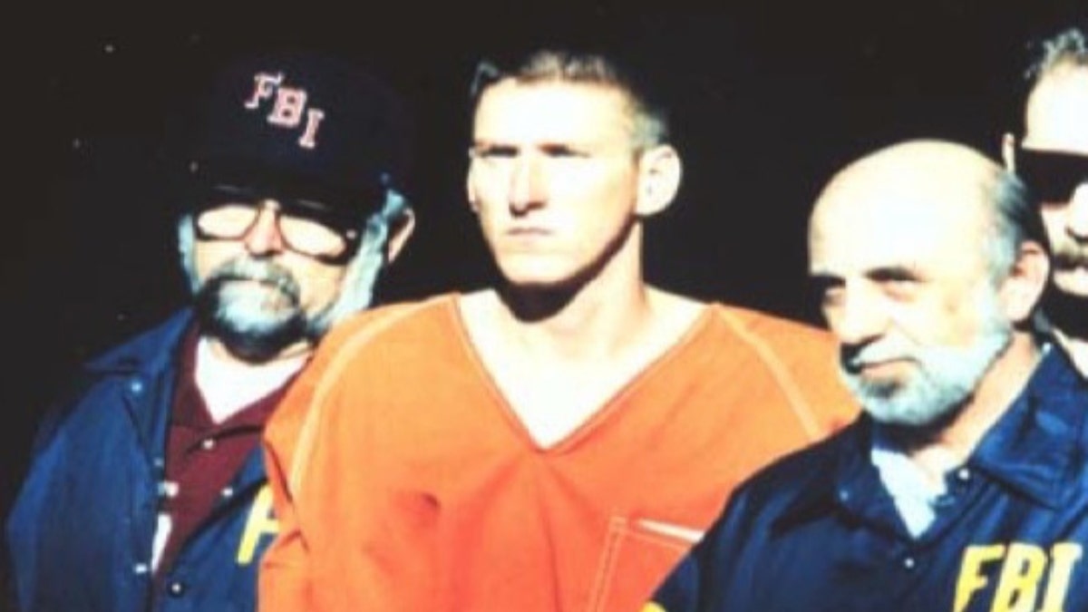 FBI agents stand next to Timothy McVeigh wearing an orange jumpsuit
