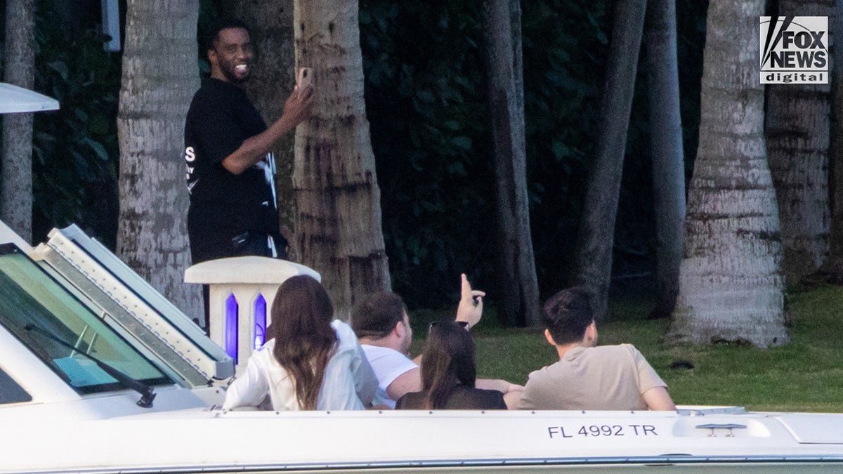 Sean "Diddy" Combs smiles at boaters as they pass by his Star Island home in Miami Beach, Florida