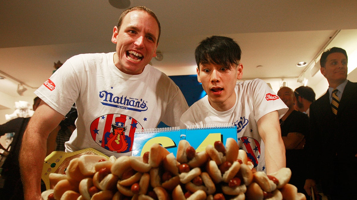 Takeru Kobayashi and Joey Chestnut in front of hot dogs