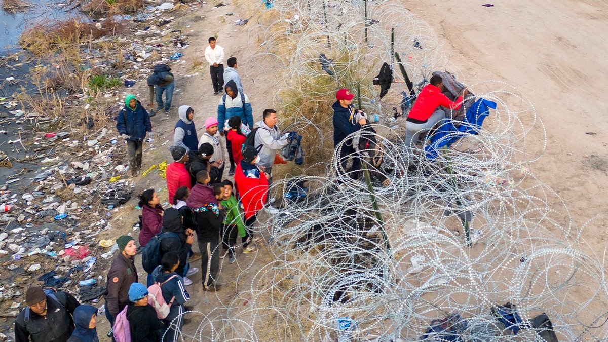 Immigrants try to pass over razor wire after crossing the border into El Paso, Texas, on Jan. 31. Those who managed to get through the wire were then allowed to proceed for further processing by U.S. Border Patrol agents.