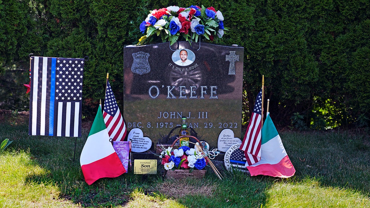 Flags, flowers and remembrances flank the headstone of John O'Keefe, a Boston police officer
