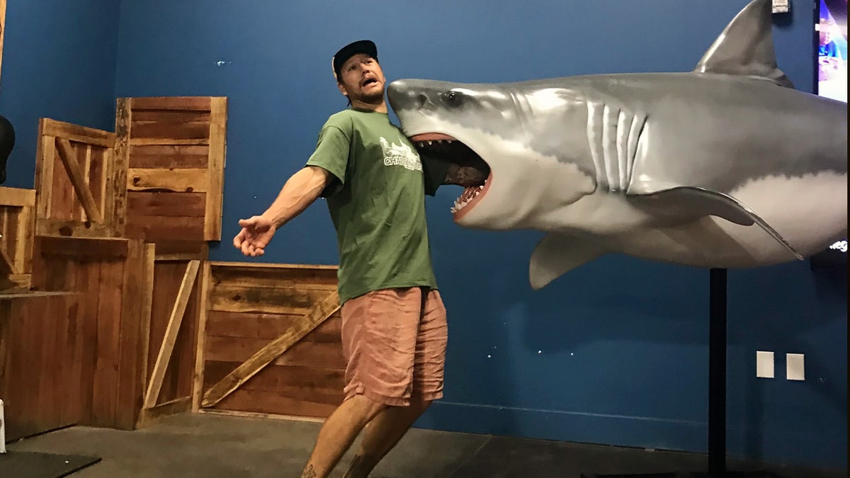 Jared Trainor poses in front of a Great White Shark