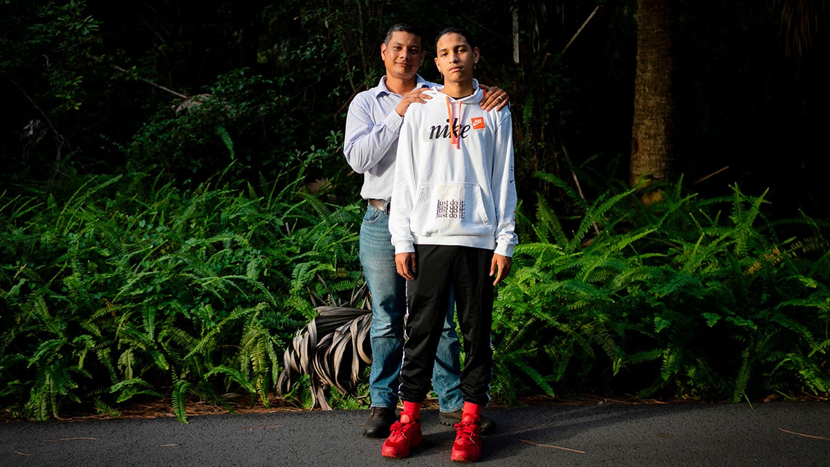 Father and son pose for photo outdoors.