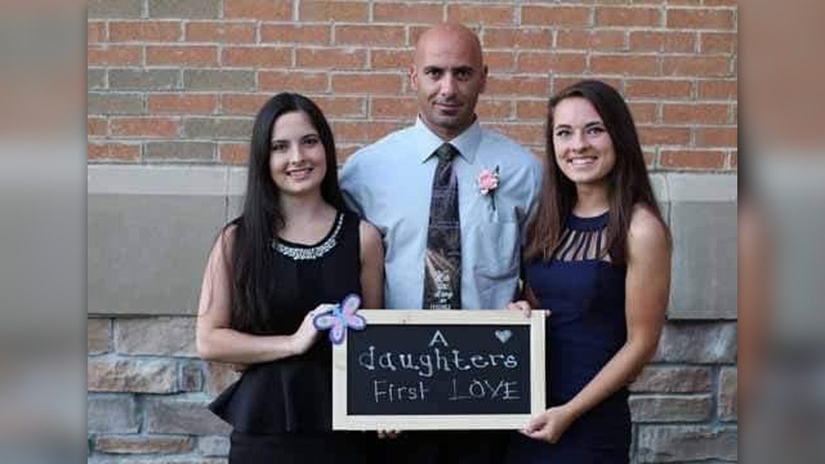 Comperatore and daughters holding a sign calling their dad their "first love"