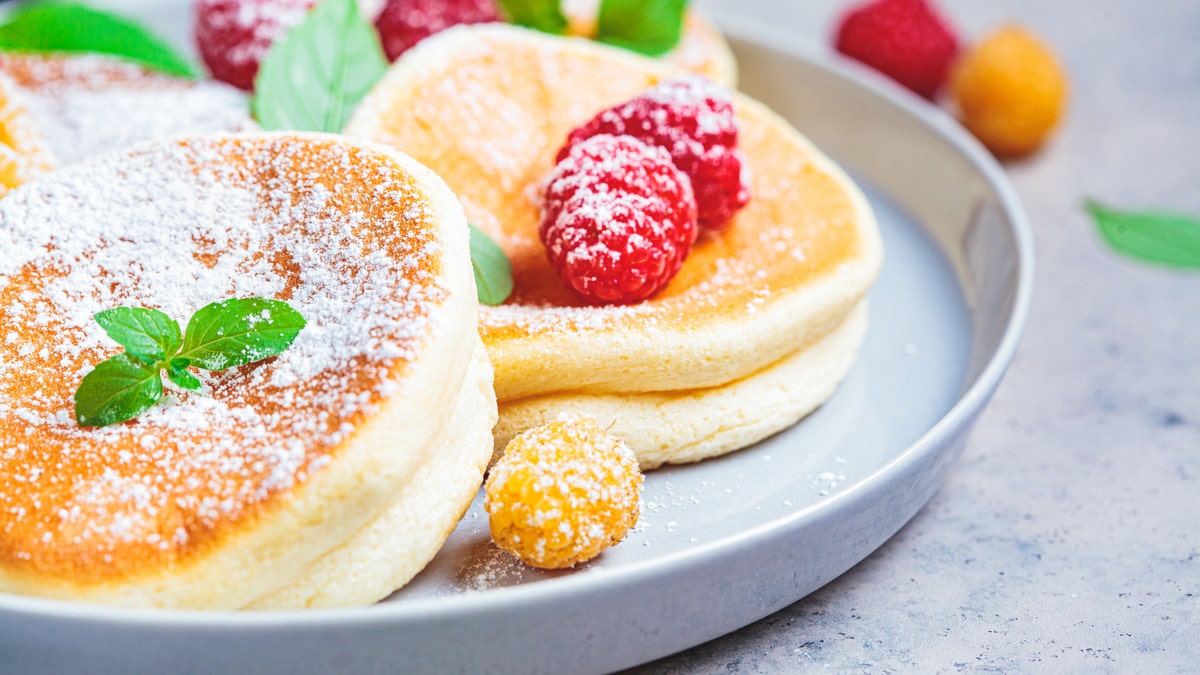 A plate of Japanese soufflé pancakes with raspberries is visible.