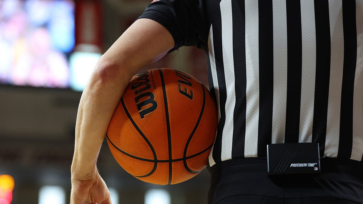 Referee holds basketball under arm