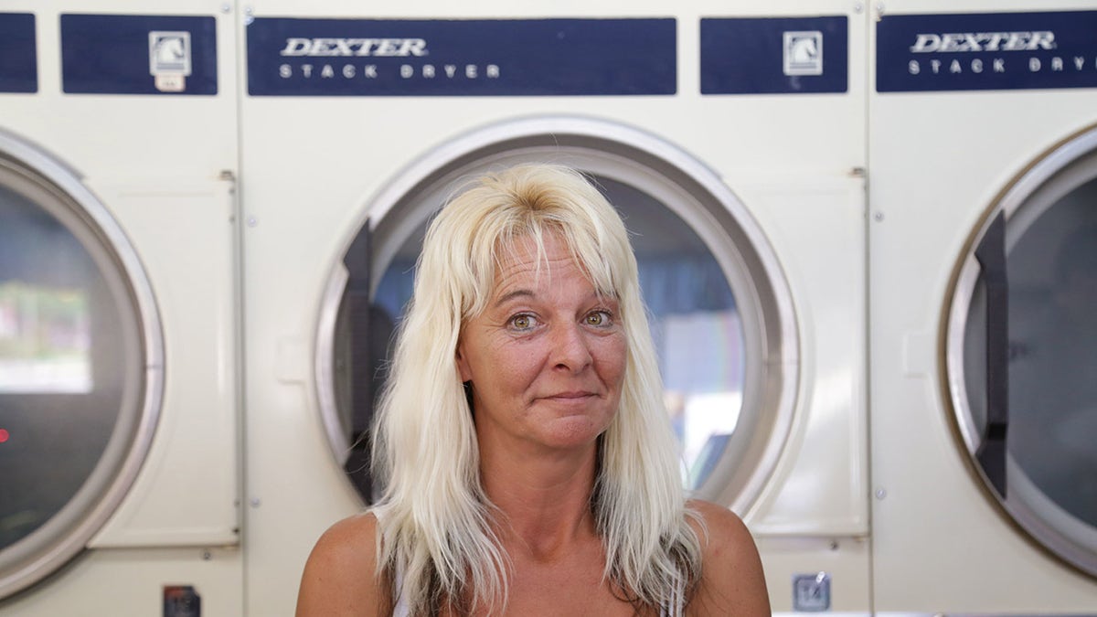 A woman standing in front of a washing machine.