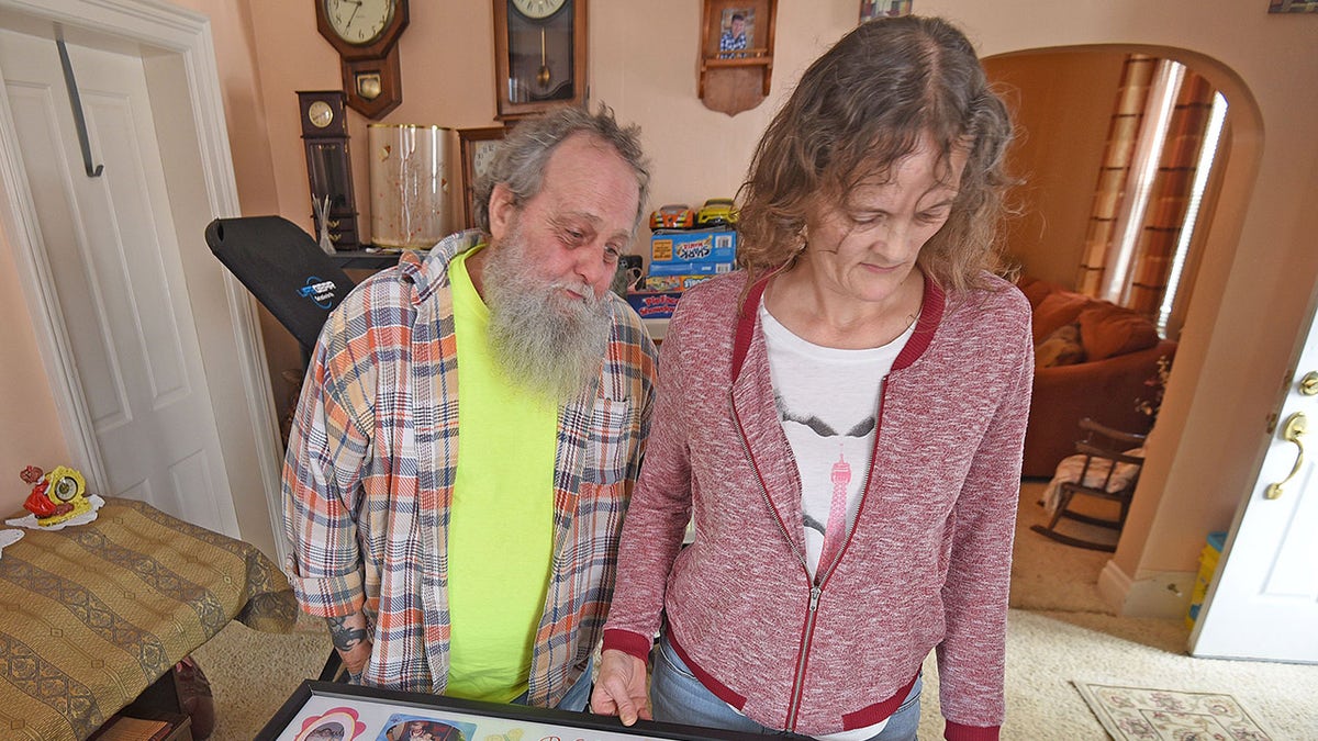 Rebekah Leicy appearing heartbroken as they look at photo albums containing photos of their late child.