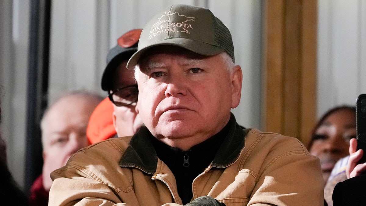 Tim Walz in barn coat and cap in closeup shot