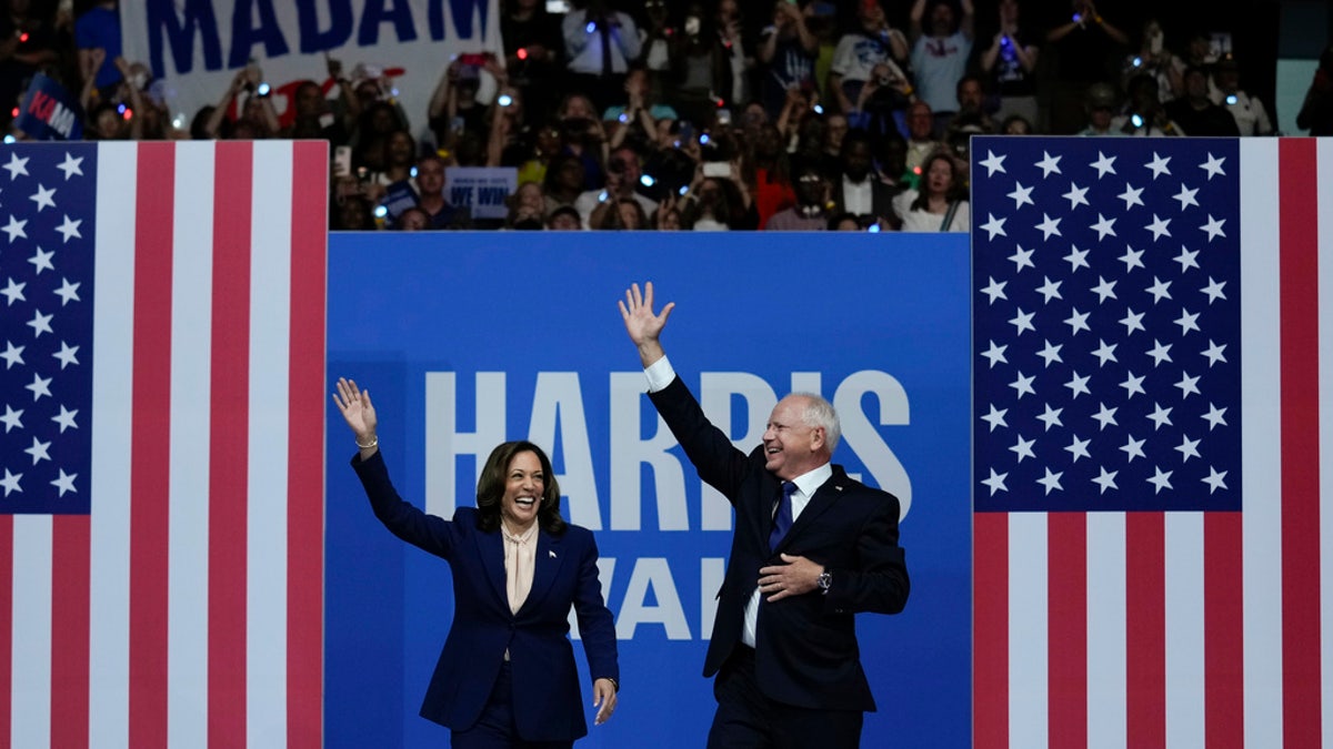 Harris and Walz waving to rallygoers from stage