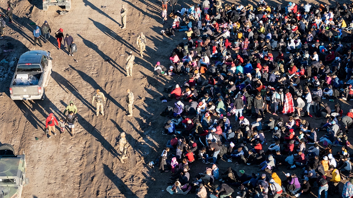 As seen from an aerial view, Texas National Guard troops watch over more than 1,000 immigrants who had crossed the Rio Grande overnight from Mexico on Dec. 18, 2023 in Eagle Pass, Texas.