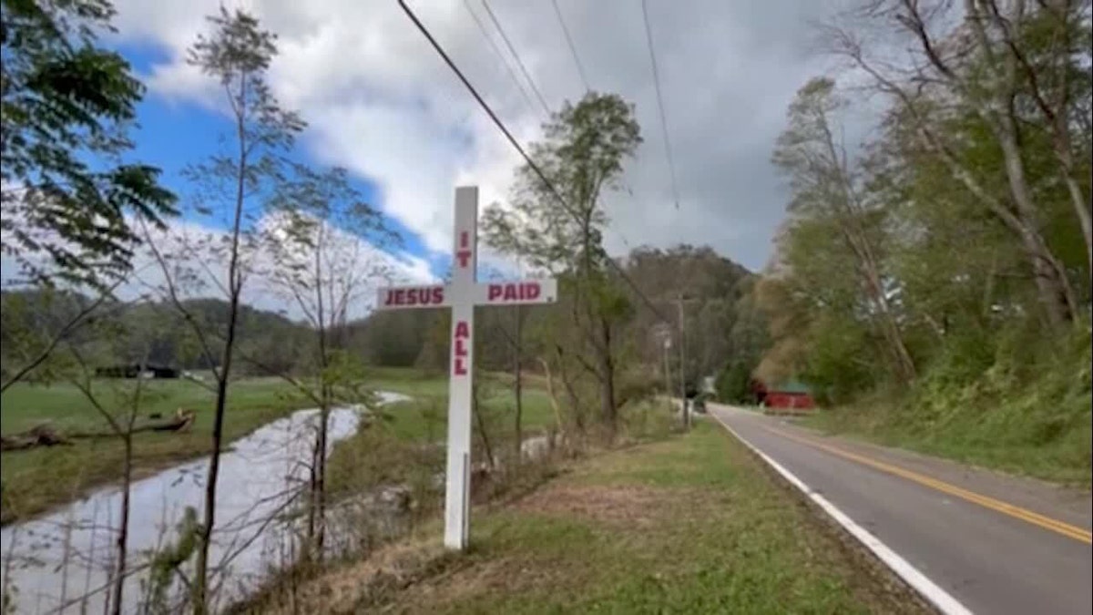 Cross on side of road reading "Jesus Paid it All"