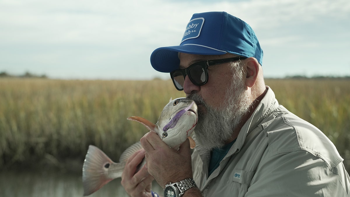 Andrew Zimmern kissing a fish he caught.