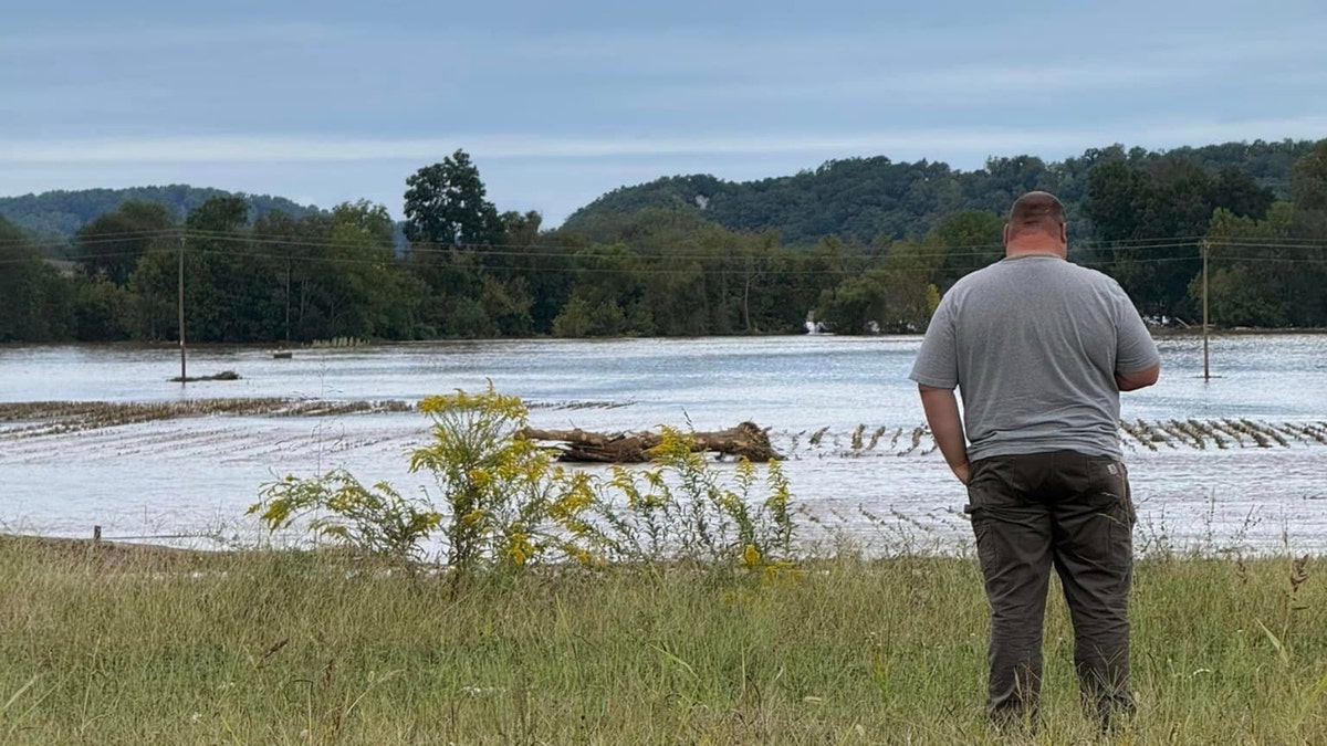 A man looks over flooded farmland