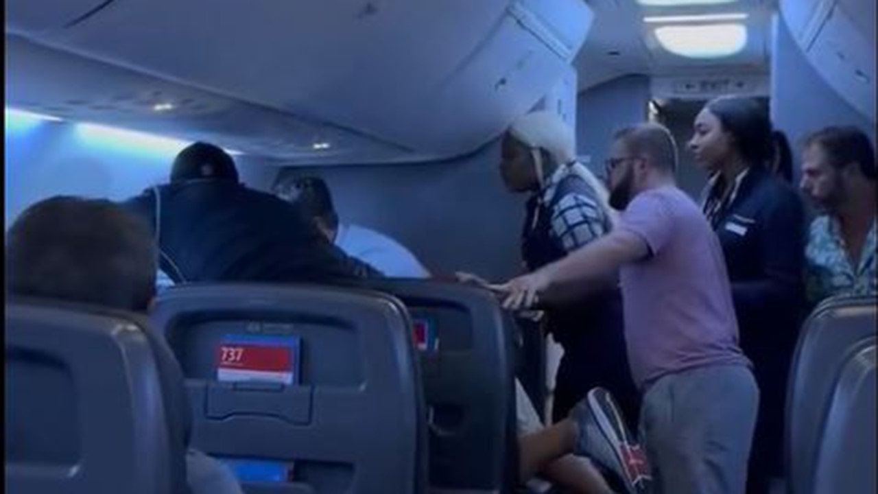 Passengers intervene on flight when man allegedly attacks woman next to him, video shows